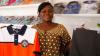 Une femme africaine tient dans la main un polo blanc et orange